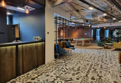 Reception area with a wood-panelled desk and patterned tile flooring leading to a lounge.