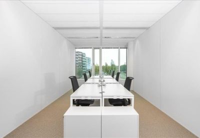 Bright, narrow office workspace with desks positioned against large windows.