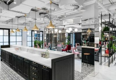 Modern communal kitchen and cafe area with a long black island and industrial ceiling details.