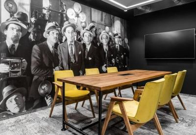 Meeting room featuring a wooden table, yellow chairs, and a black-and-white cinematic wall mural.