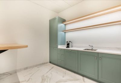 Minimalist kitchen area with sage green cabinets and marble floors.