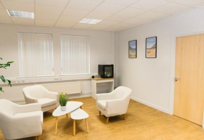 Bright break room featuring white bucket chairs and a small coffee table.