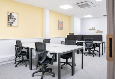 Bright coworking area with white desks, ergonomic chairs, and yellow feature walls.
