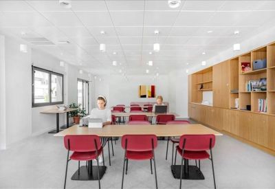 Bright training room with long tables, red chairs, and light wood shelving.