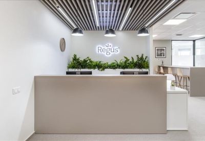 Bright reception desk with hanging pendant lights, indoor plants, and branded signage.