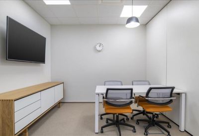 Bright private office with four desks, wall-mounted TV, and wooden storage cabinet.