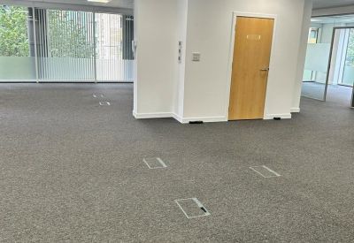 Spacious open-plan office area with grey carpeting and white walls.