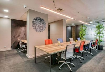 Collaborative workspace with a long wooden table and ergonomic chairs in various colors.