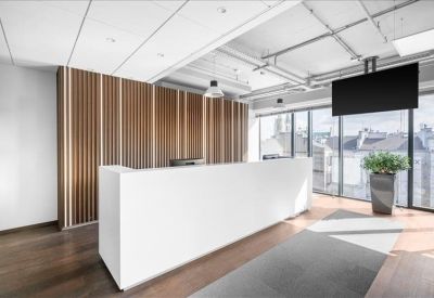 Bright reception area with a minimalist white desk, wood-paneled wall, and city views.
