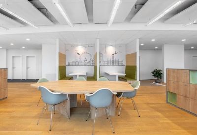 Spacious breakout area featuring a large wooden table and city skyline murals.