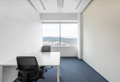 Bright corner office suite with two workstations and a city view through large windows.