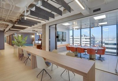 Long wooden communal table and a glass-walled conference room with orange seating.