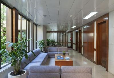 Long reception lobby with a large blue sofa, wooden coffee table, and indoor plants.