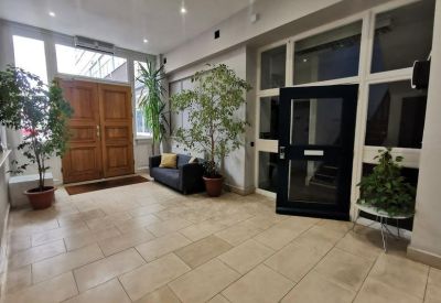 Spacious reception area of Princess House with wooden double doors, potted plants, and a comfortable waiting sofa.