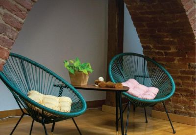 Arched brick-walled breakout area with teal string chairs and a wooden coffee table.