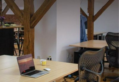Bright attic workspace with a laptop on a wooden desk and ergonomic mesh office chairs.