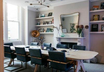 Elegant meeting room with a large oval table, teal leather chairs, and a feature mirror.