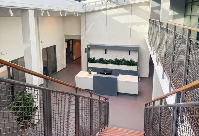Bright, modern reception area with wooden stairs and a sleek white front desk at Propellervägen 6A, Täby.