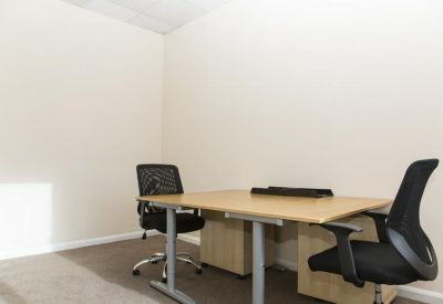 Private office featuring a wooden desk and two black mesh ergonomic chairs.