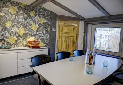 Meeting room with a white table, blue water glasses, and floral wallpaper.