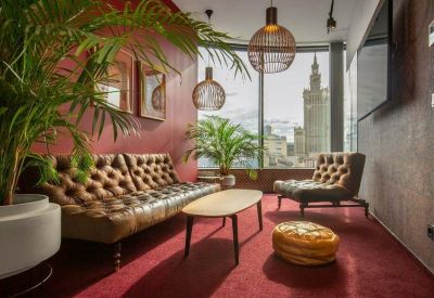 Stylish lounge area with leather tufted sofas, warm lighting, and a view of the Palace of Culture and Science.
