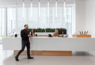Modern white reception desk with minimalist vertical lighting and indoor plants.