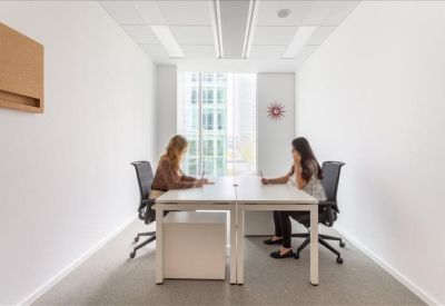 Private two-person office suite with white desks and large windows.