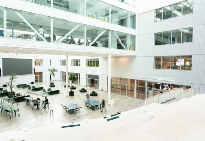 High-angle view of a large white atrium with trees and ping pong tables.