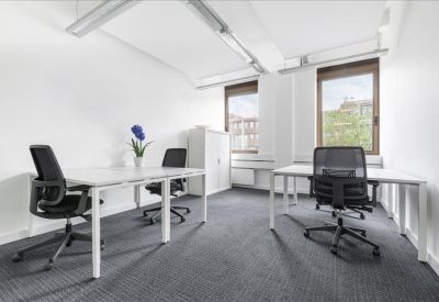 Spacious two-desk office setup with ergonomic black chairs and large windows.
