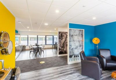 Colorful breakout area with yellow and blue walls, comfortable armchairs, and musical instrument wall decor.