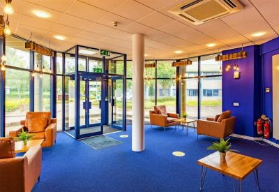 Vibrant blue reception area with comfortable leather armchairs and floor-to-ceiling windows.