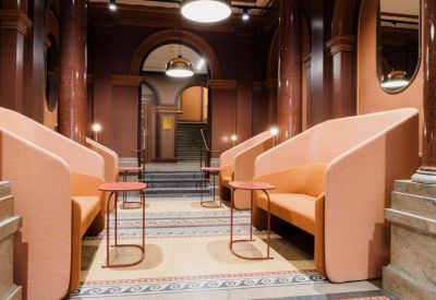 Waiting area featuring high-backed orange privacy sofas and marble pillars.