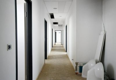 Bright white corridor with multiple office doors and storage equipment.