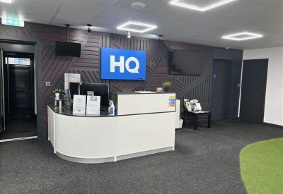 Modern reception desk with branded blue signage and a dark textured feature wall.