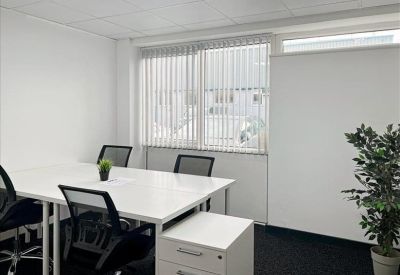 Bright private office with a white four-person desk and vertical window blinds.