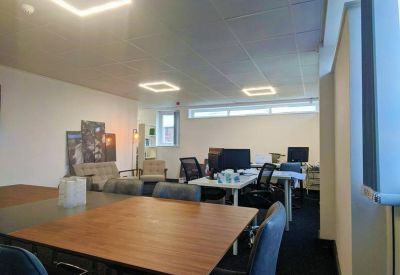 Office lounge and breakout area with wooden tables, soft seating, and feature wall art.