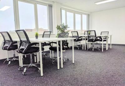 Spacious open-plan workspace with multiple desks and large windows.