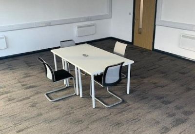 Spacious interior office suite with grey patterned carpeting and white walls.