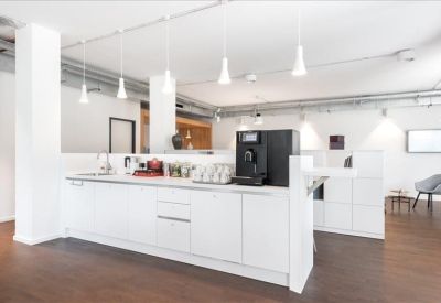 Modern office kitchen and breakout area with a sleek white counter and coffee machine.