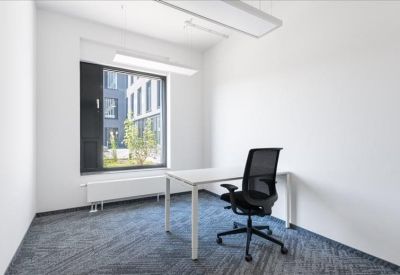 Bright private office featuring a white desk and ergonomic chair by a large window.
