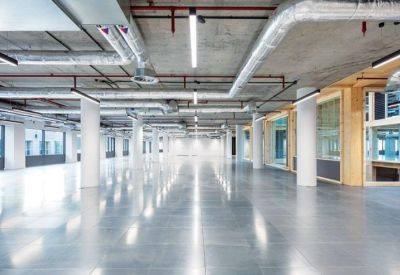 Vast empty open-plan floor with polished concrete floors and exposed ceiling pipes.
