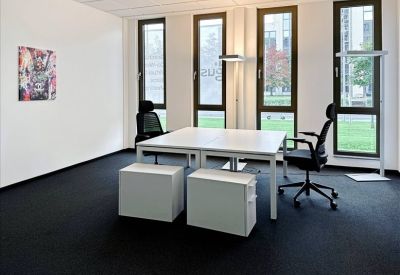 Private office featuring white desks, black chairs, and natural light from large windows.