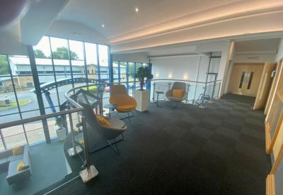 Mezzanine breakout area with glass railings and yellow seating overlooking the entrance.