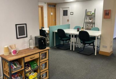 Communal breakout area with a coffee station, snacks, and a large white collaboration table.