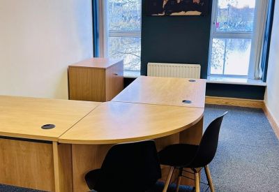 Bright office suite featuring curved wooden desks and a world map wall graphic by the window.
