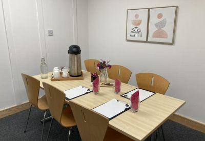 Formal meeting room with a light wood table, several chairs, and colourful abstract wall art.