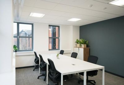 Bright open-plan office suite with a large white shared desk and ergonomic chairs.