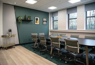 Modern boardroom with a long dark table and teal accent wall.