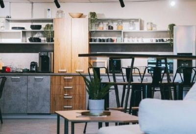 Modern office kitchen and breakout area with wooden cabinetry and bar seating.