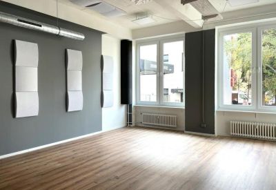 Spacious room with wood-style flooring, acoustic wall panels, and ample natural light.